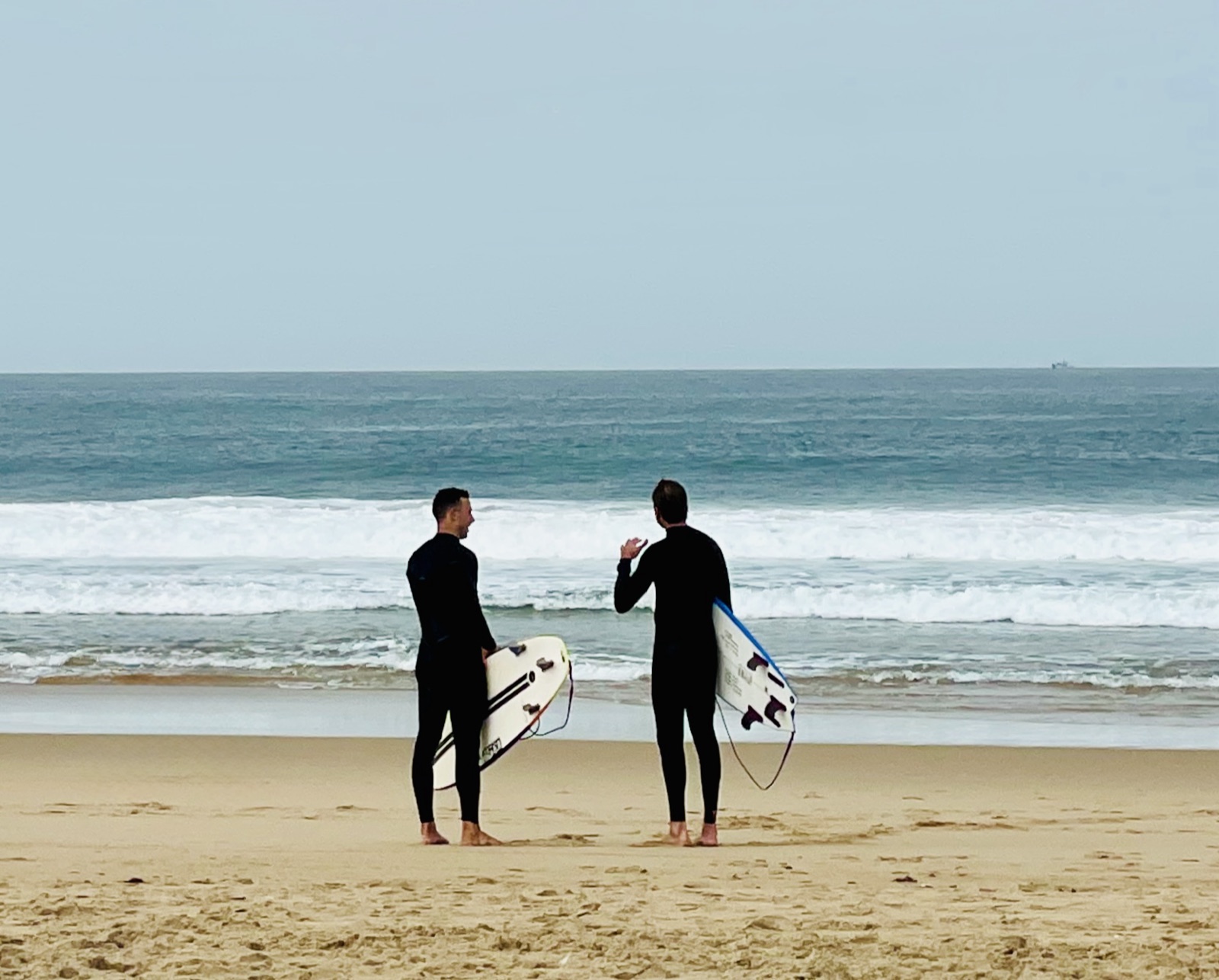 Two surfers talking on the beach