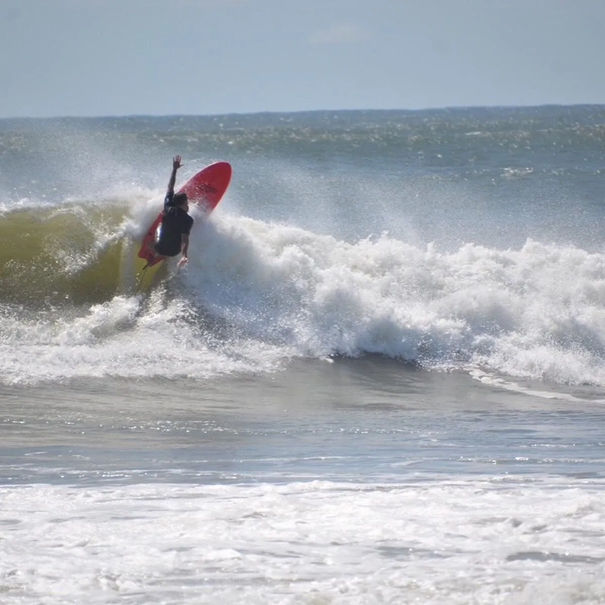Surfer on a red board carving a wave